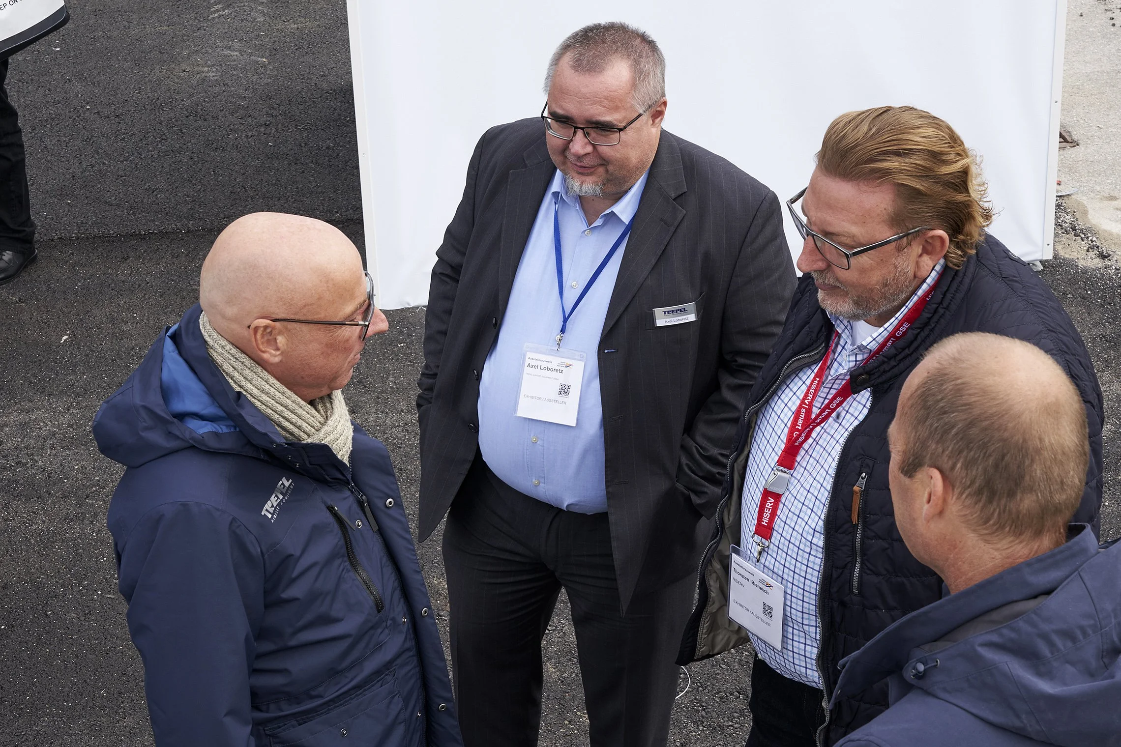 Four men engaged in a professional conversation on the exhibition grounds at the TREPEL stand