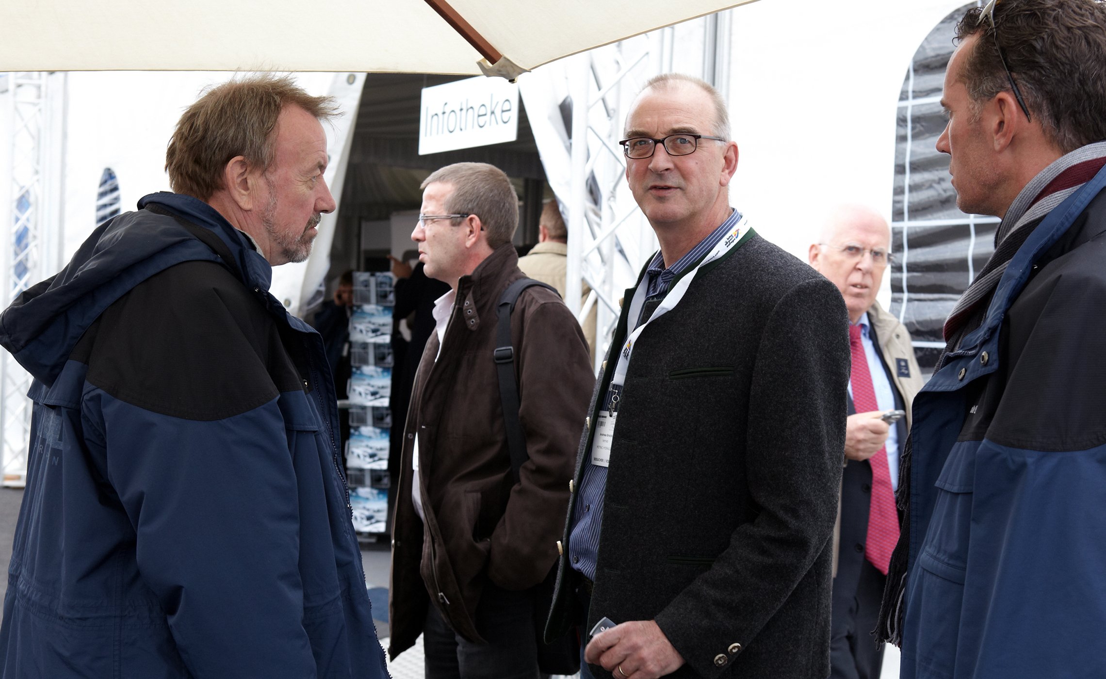 Gruppe von Männern im Gespräch vor dem TREPEL-Messezelt mit sichtbarer Infotheke im Hintergrund