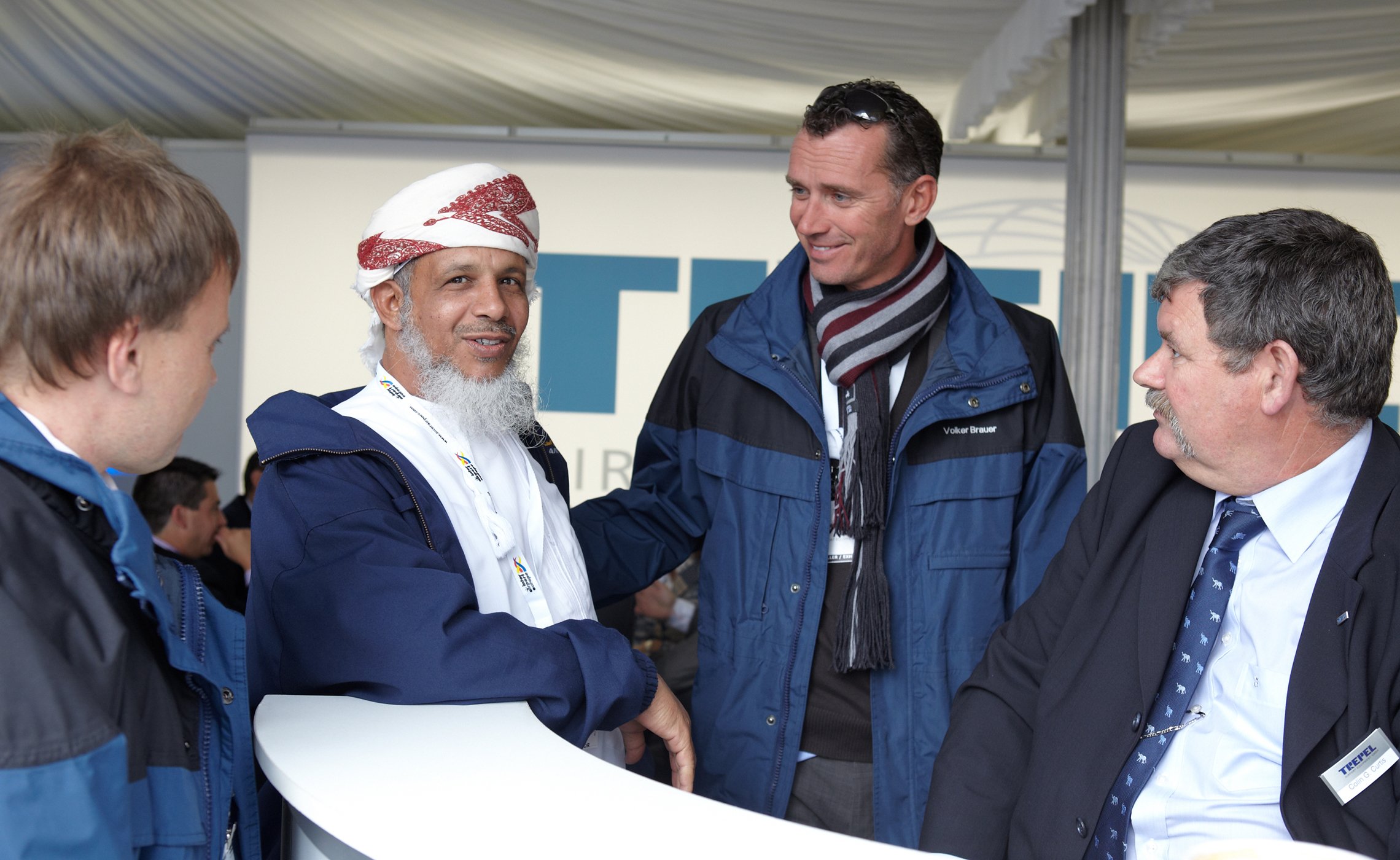 Vier Männer im Gespräch an einem weißen Tresen auf dem TREPEL-Messestand
