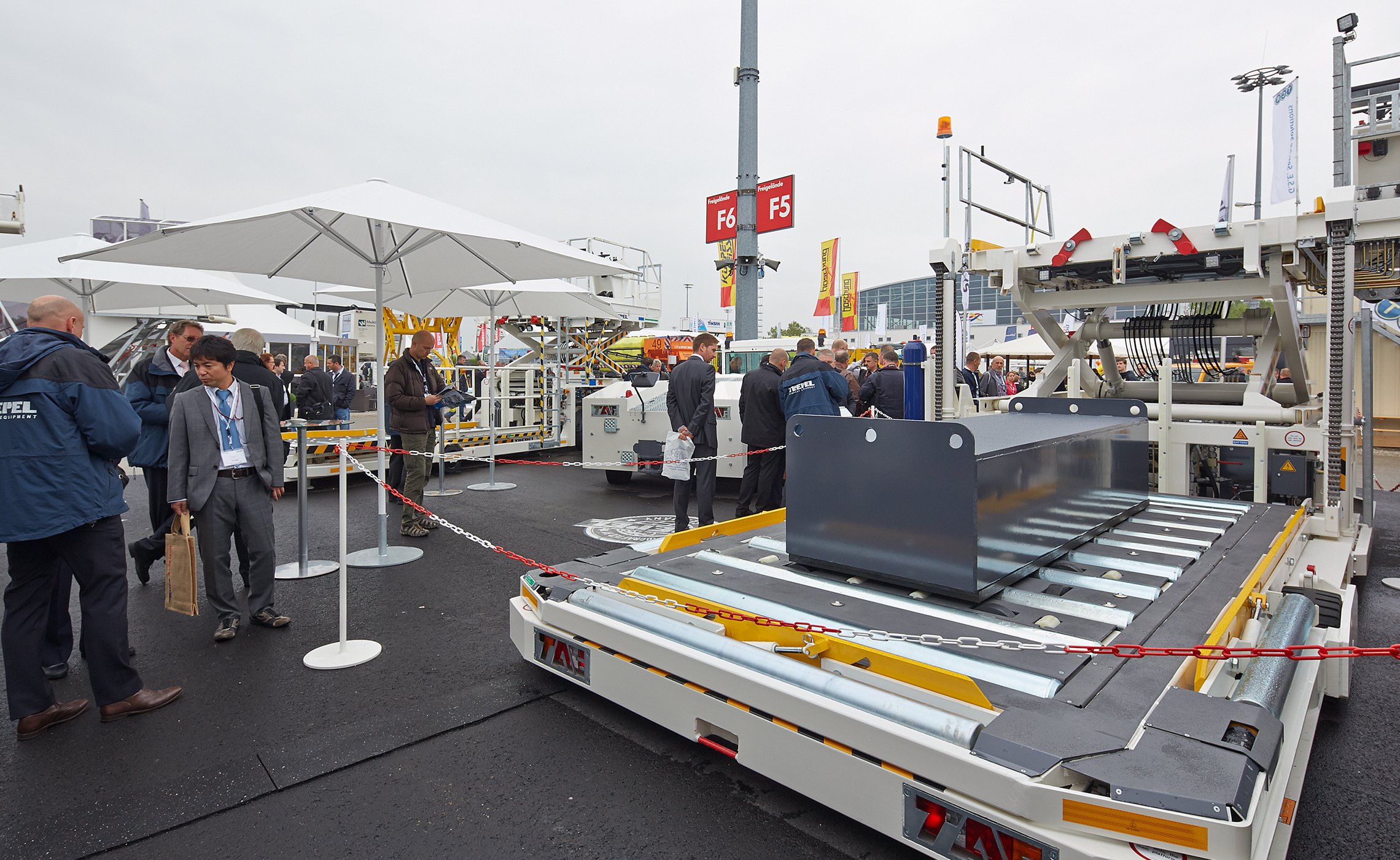 Besucher begutachten CHAMP High Loader von TREPEL auf dem Messegelände unter weißen Sonnenschirmen