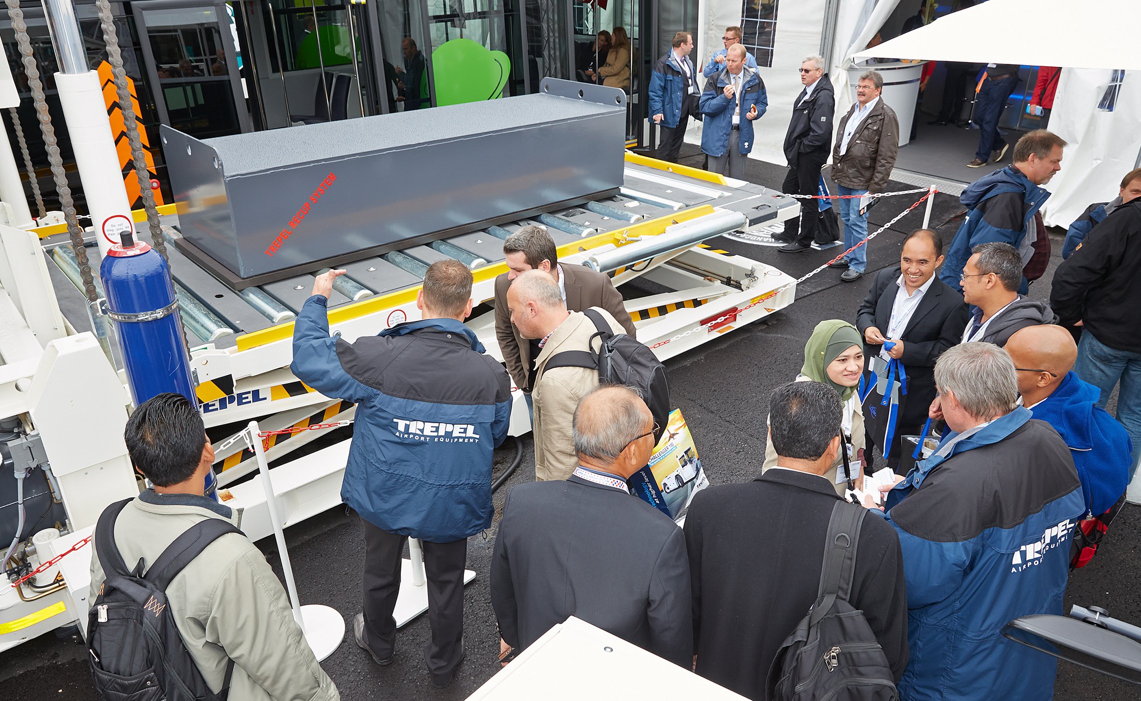 Besuchergruppe im Gespräch vor einer Ladeplattform mit TREPEL-Automatic-Load-System