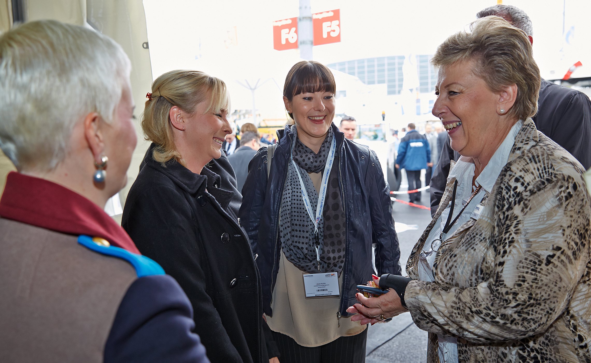 Vier Frauen im Gespräch auf einer Messe, lachend und einander zugewandt