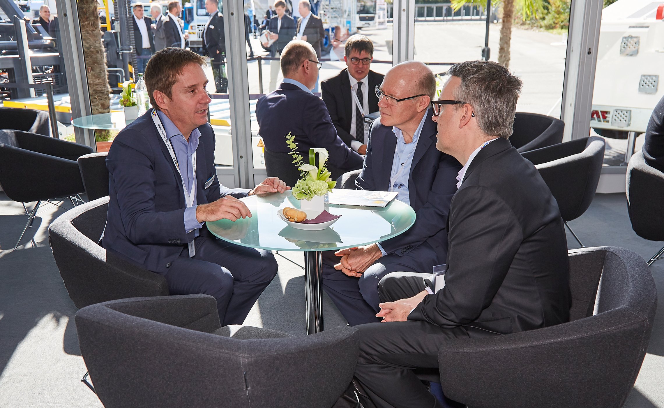 Four men in suits seated at a round table in the TREPEL lounge during a trade fair meeting