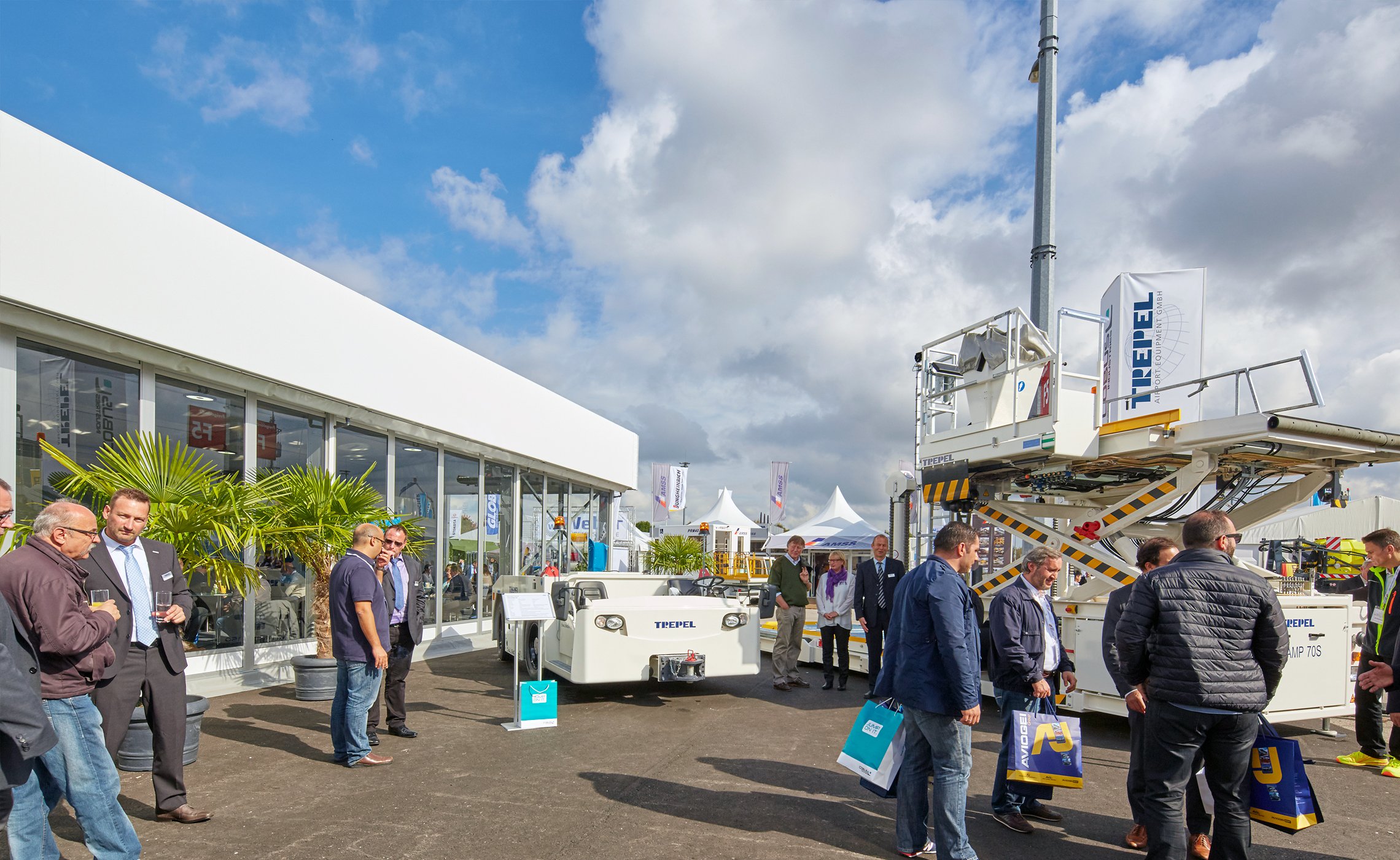 Besucher stehen im Außenbereich einer Messe vor TREPEL Bodenabfertigungsfahrzeugen