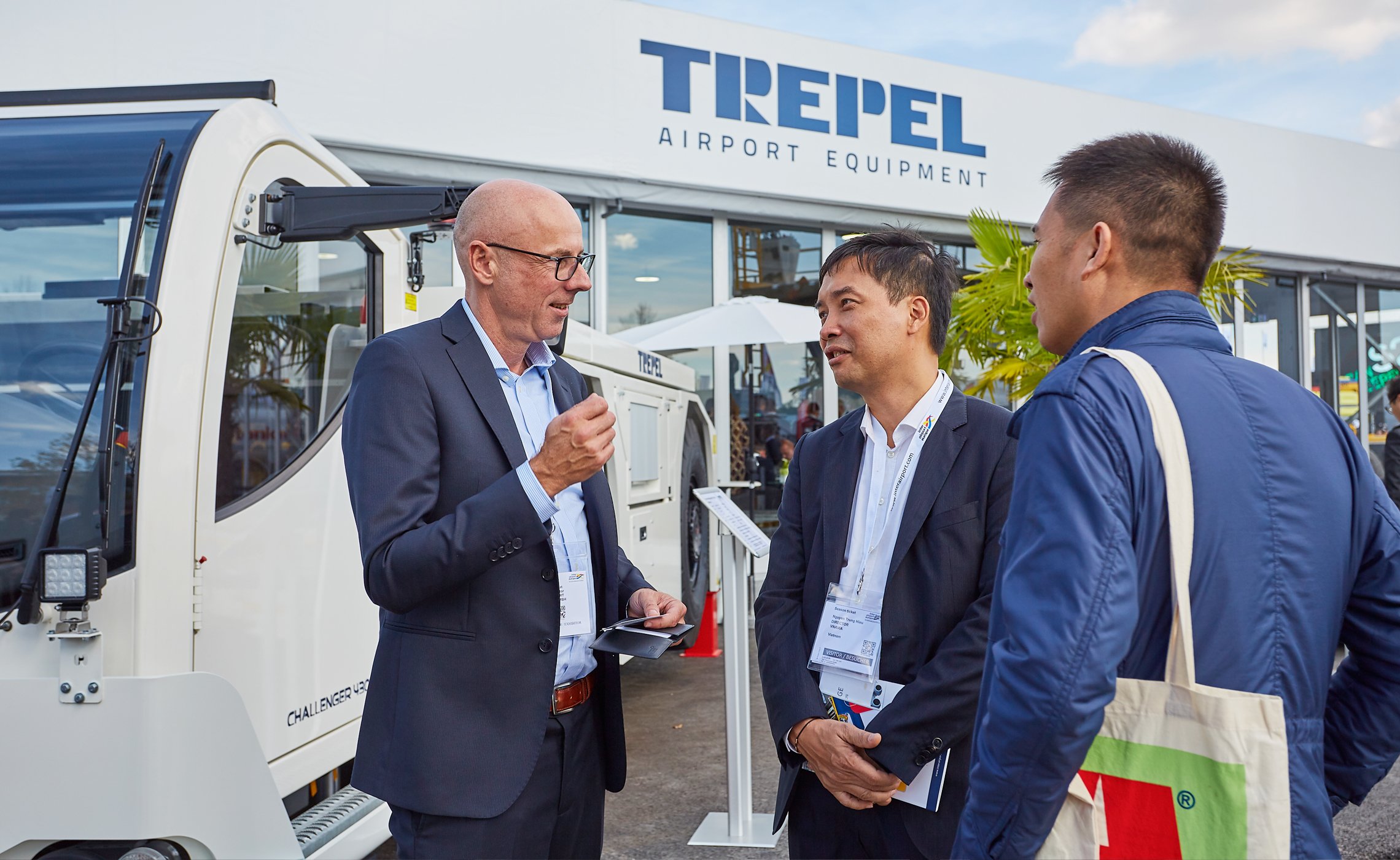 Drei Männer im Gespräch vor einem Fahrzeug am TREPEL-Messestand