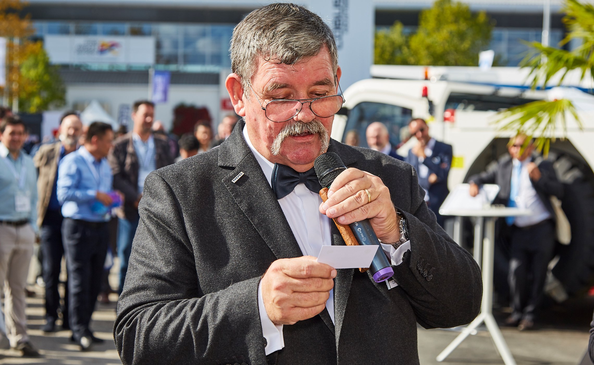 Mann im Anzug mit Mikrofon liest Gewinnerkarte vor