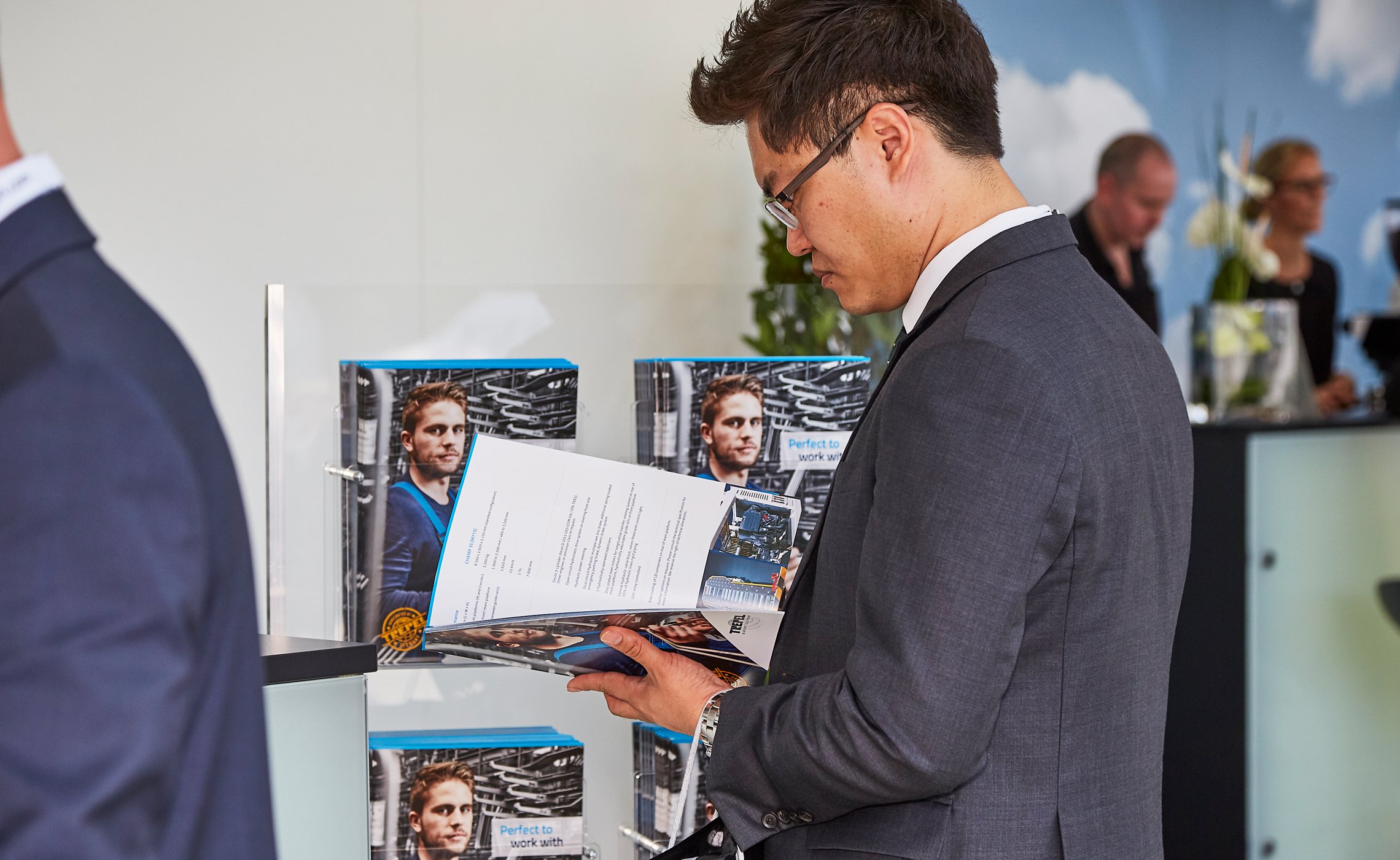 Geschäftsmann liest am Messestand eine Informationsbroschüre von TREPEL