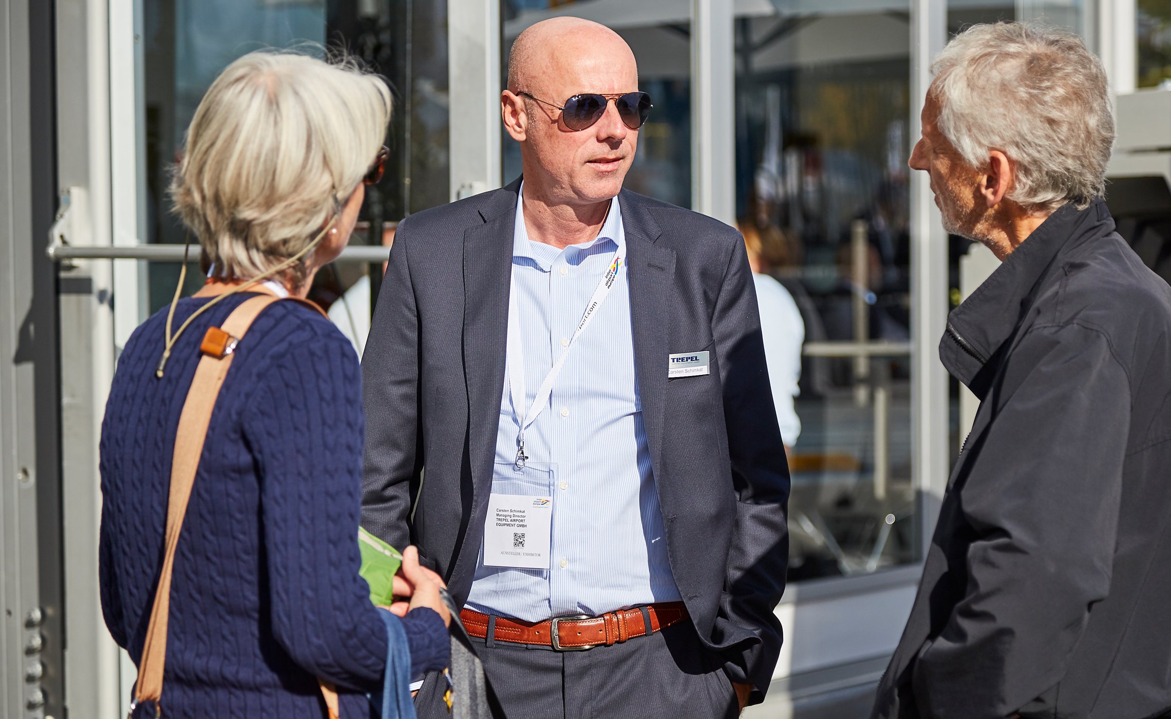 TREPEL-Mitarbeiter im Anzug im Gespräch mit zwei Messebesuchern im Außenbereich